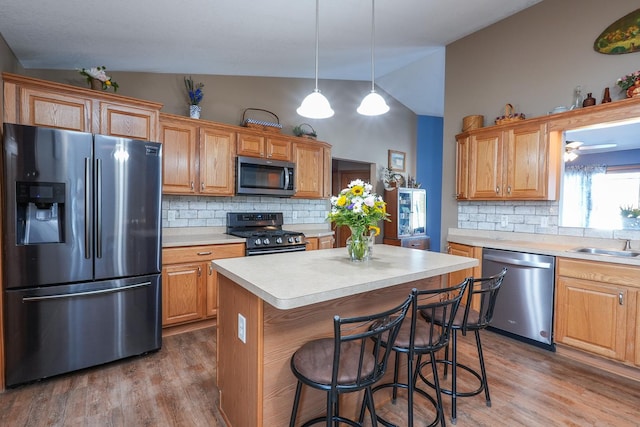 kitchen featuring stainless steel appliances, backsplash, vaulted ceiling, pendant lighting, and a center island