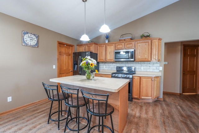 kitchen with hardwood / wood-style flooring, appliances with stainless steel finishes, decorative backsplash, lofted ceiling, and pendant lighting