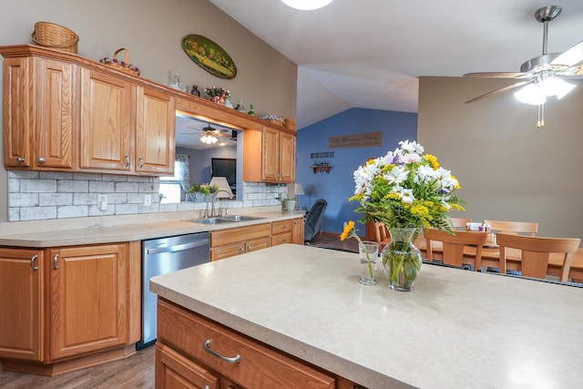 kitchen with vaulted ceiling, dishwasher, light hardwood / wood-style floors, decorative backsplash, and sink