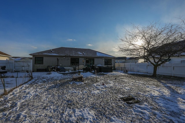 snow covered back of property with a hot tub