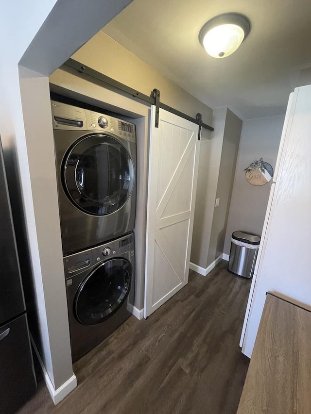 laundry room with dark wood-type flooring, stacked washer and dryer, and a barn door