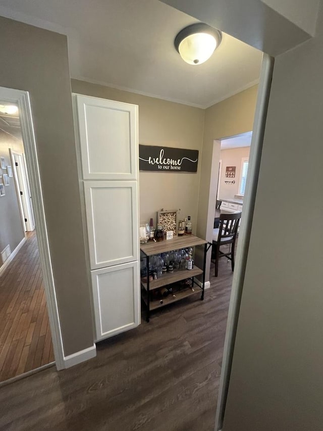 corridor with dark hardwood / wood-style floors and crown molding