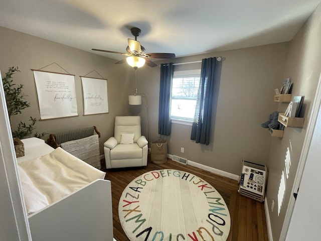 bedroom featuring ceiling fan, dark wood-type flooring, and a nursery area