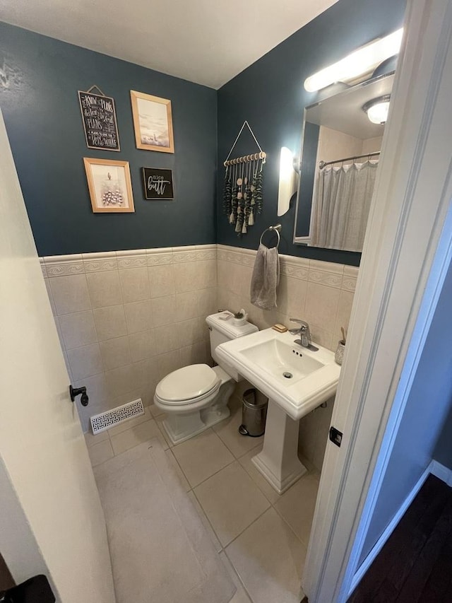 bathroom featuring tile walls, toilet, and tile patterned flooring