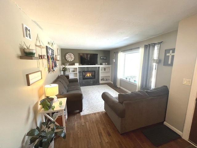 living room with a tiled fireplace, a textured ceiling, and dark hardwood / wood-style floors