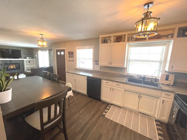 kitchen with a wealth of natural light, black dishwasher, hanging light fixtures, sink, and white cabinets