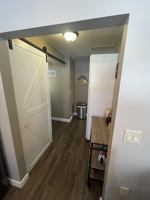 hall featuring a barn door and dark wood-type flooring