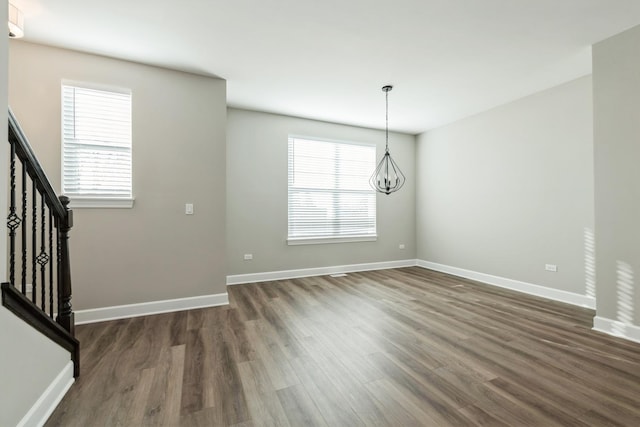 unfurnished dining area featuring dark wood-type flooring, a chandelier, and a healthy amount of sunlight