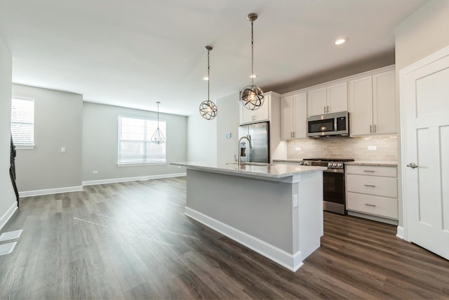 kitchen with white cabinets, appliances with stainless steel finishes, an island with sink, sink, and hanging light fixtures