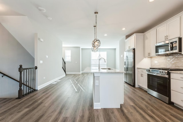 kitchen featuring pendant lighting, sink, white cabinetry, appliances with stainless steel finishes, and an island with sink