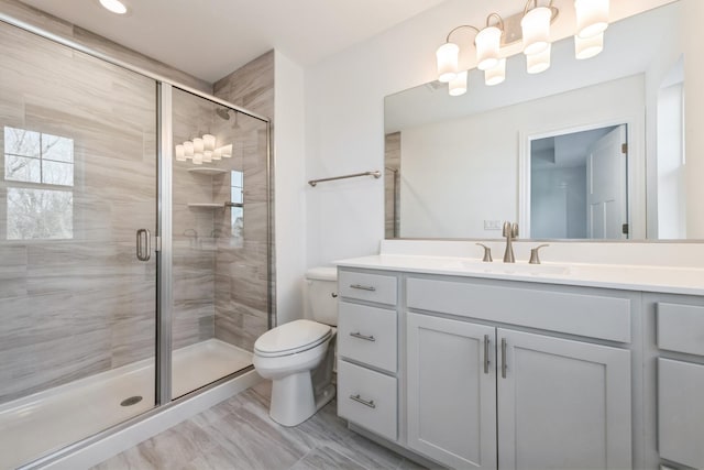 bathroom with toilet, a shower with door, and vanity