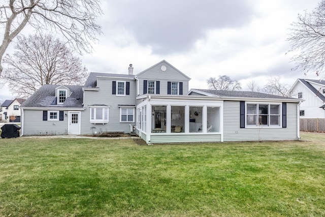 rear view of property featuring a sunroom and a lawn