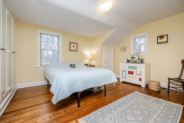 bedroom with multiple windows, wood-type flooring, and lofted ceiling