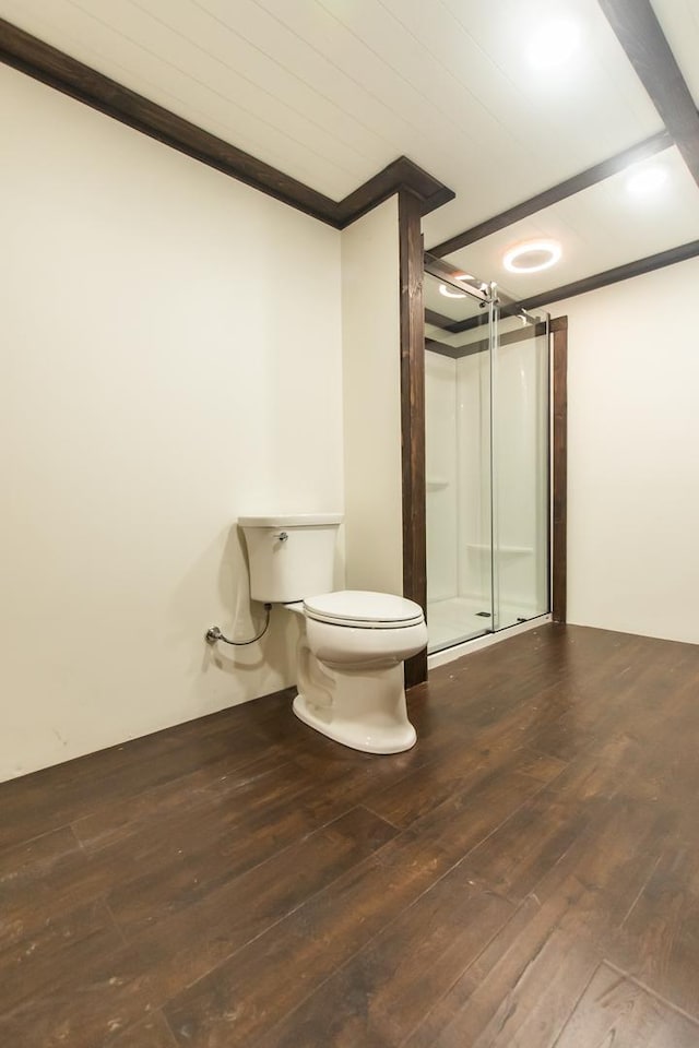 bathroom with toilet, crown molding, wood-type flooring, and a shower with door