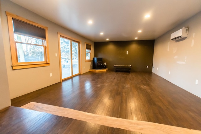 interior space featuring dark hardwood / wood-style flooring, a wall mounted AC, and a wood stove