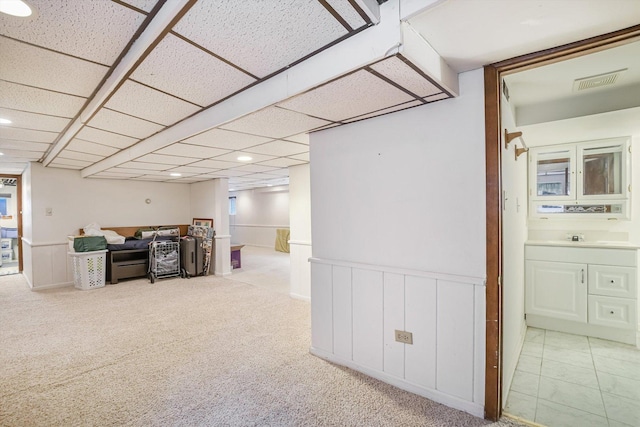 basement with light carpet, a paneled ceiling, and sink