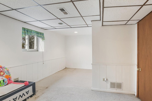 basement with a drop ceiling and light carpet