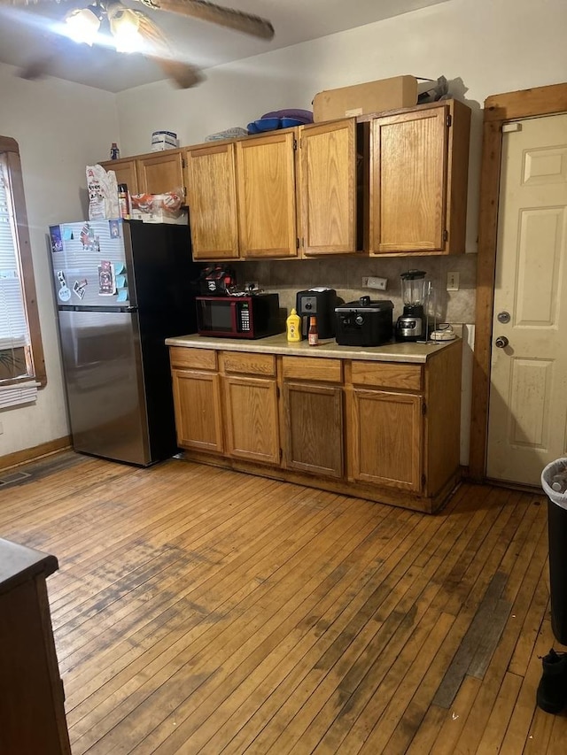 kitchen featuring ceiling fan, stainless steel refrigerator, and light hardwood / wood-style flooring