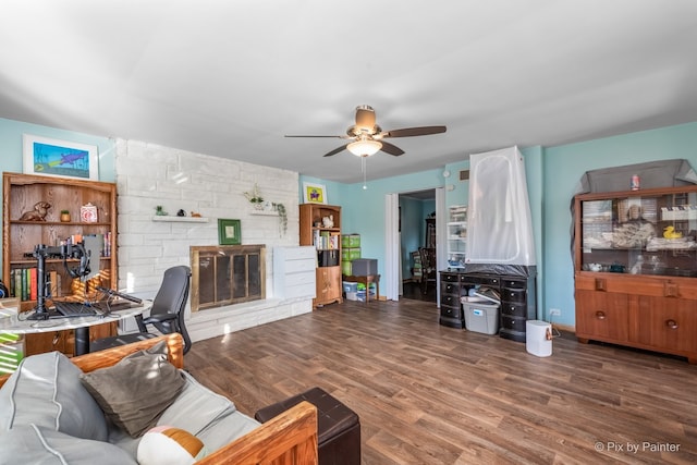 living room featuring ceiling fan, a stone fireplace, and hardwood / wood-style floors