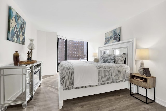 bedroom with dark wood-style floors, multiple windows, and baseboards