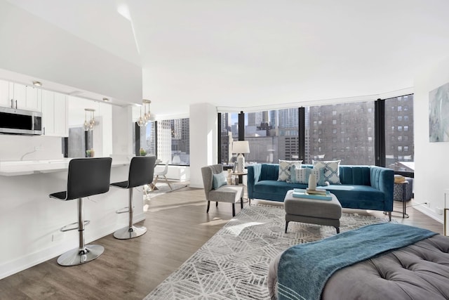 living area with light wood-type flooring, a view of city, baseboards, and an inviting chandelier