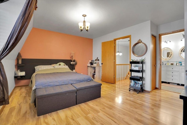 bedroom featuring light wood-type flooring, a chandelier, and connected bathroom