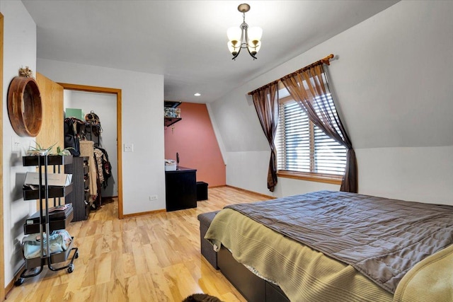 bedroom featuring vaulted ceiling, a closet, a chandelier, and light wood-type flooring