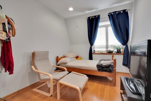 bedroom with vaulted ceiling and light hardwood / wood-style flooring