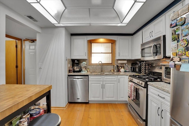 kitchen featuring sink, white cabinets, light stone countertops, and stainless steel appliances