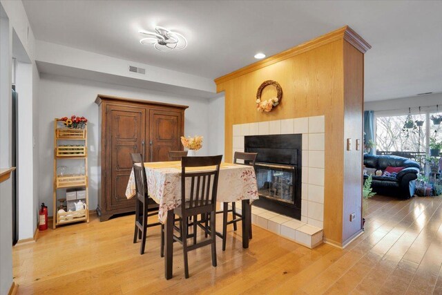 dining space featuring a tile fireplace and light hardwood / wood-style floors