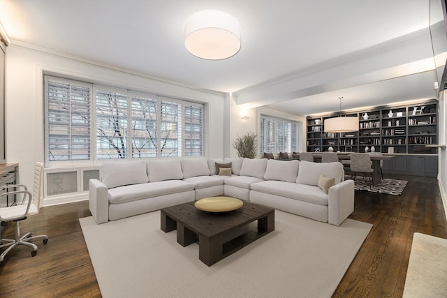 living room featuring built in features, dark hardwood / wood-style flooring, and ornamental molding