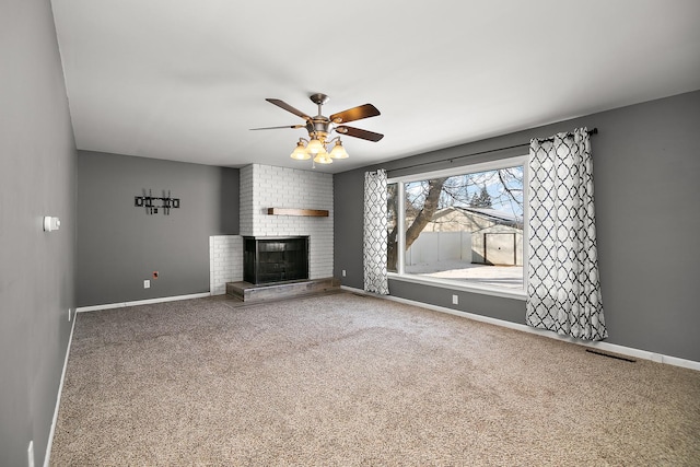 unfurnished living room with a brick fireplace, carpet floors, and ceiling fan