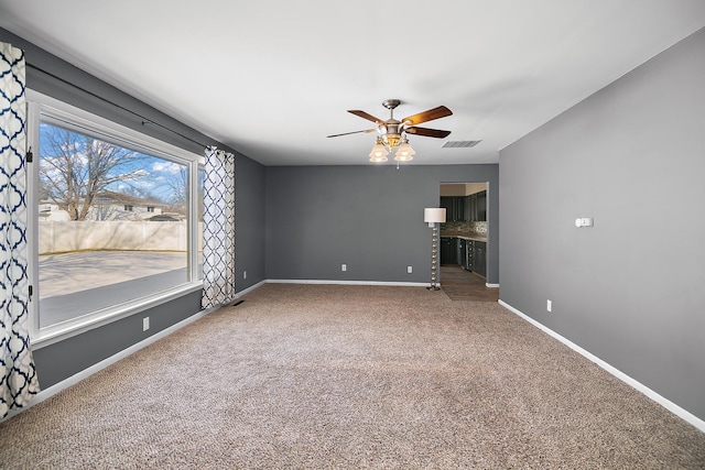 empty room featuring ceiling fan and carpet