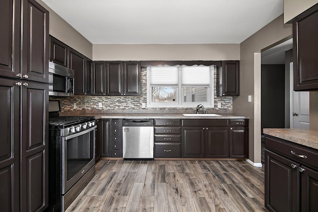 kitchen featuring sink, hardwood / wood-style flooring, backsplash, stainless steel appliances, and dark brown cabinetry