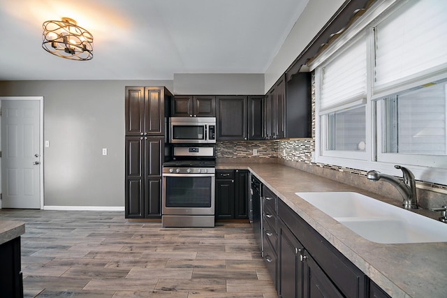 kitchen with stainless steel appliances, sink, decorative backsplash, and light hardwood / wood-style flooring