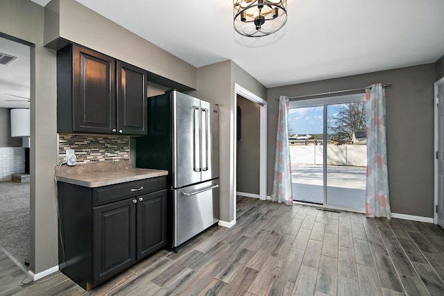 kitchen with hardwood / wood-style floors, backsplash, and stainless steel refrigerator