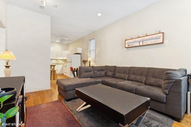 living room featuring hardwood / wood-style flooring, sink, and ceiling fan