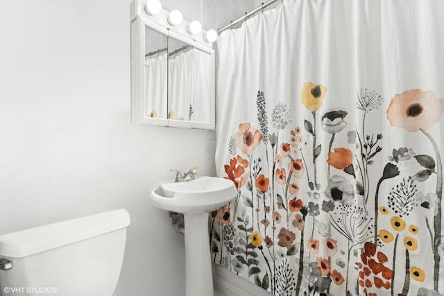 bathroom featuring toilet, a shower with curtain, and sink