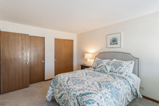 bedroom with two closets and light carpet