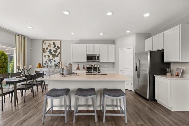 kitchen featuring white cabinets, appliances with stainless steel finishes, sink, a center island with sink, and a breakfast bar area