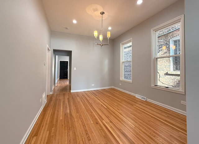 spare room featuring a chandelier and hardwood / wood-style floors