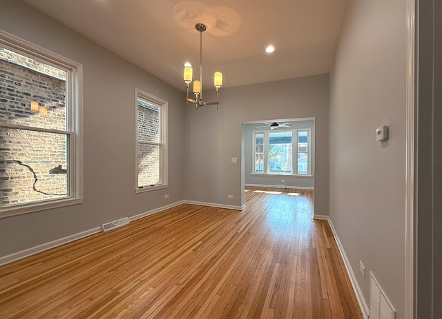 unfurnished dining area featuring a chandelier and light wood-type flooring