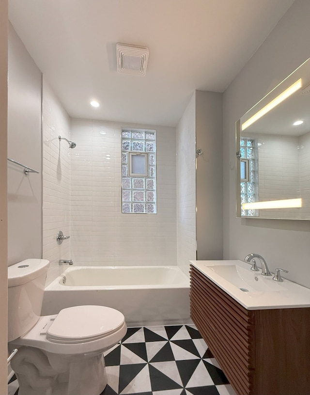 full bathroom featuring tiled shower / bath combo, vanity, and toilet