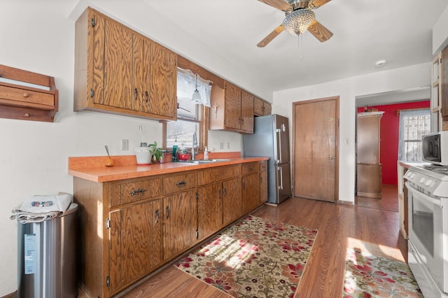 kitchen featuring dark wood-type flooring, sink, plenty of natural light, stainless steel fridge, and white range oven