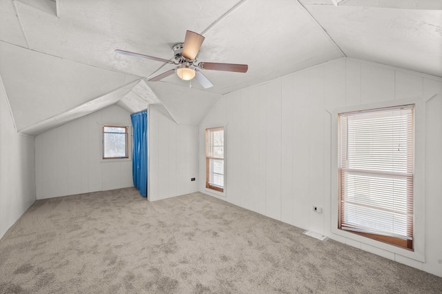 bonus room featuring vaulted ceiling, light colored carpet, and wood walls