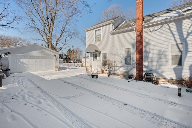 view of snow covered exterior featuring a garage and an outdoor structure