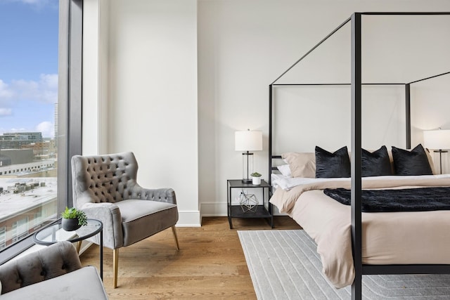 bedroom featuring baseboards, a city view, and light wood-style floors