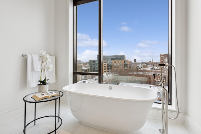 bathroom featuring a freestanding tub, a city view, baseboards, and tile patterned floors