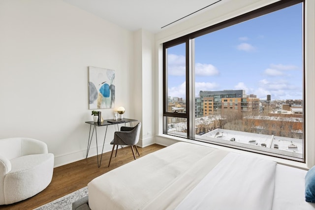 bedroom featuring baseboards, wood finished floors, and a city view