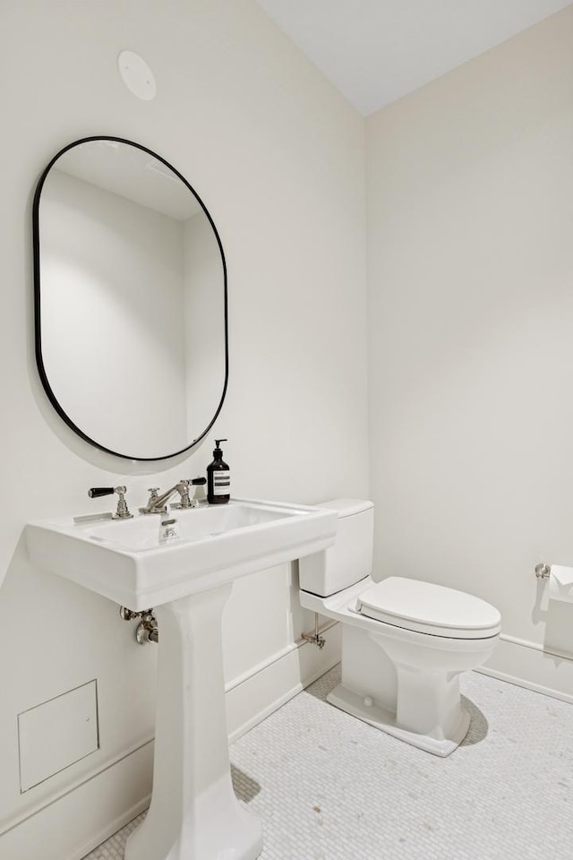 bathroom featuring toilet, tile patterned flooring, and baseboards